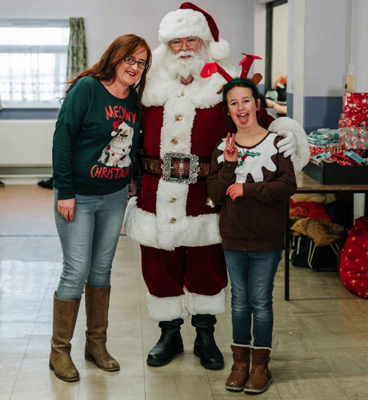Mother and daughter take a photo with Santa Claus.