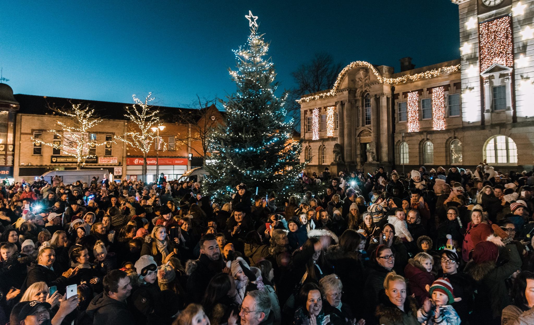 Christmas tree surrounded by people.